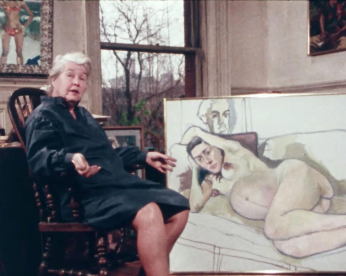 Alice Neel seated in a chair in front of a large painting of a nude pregnant woman.