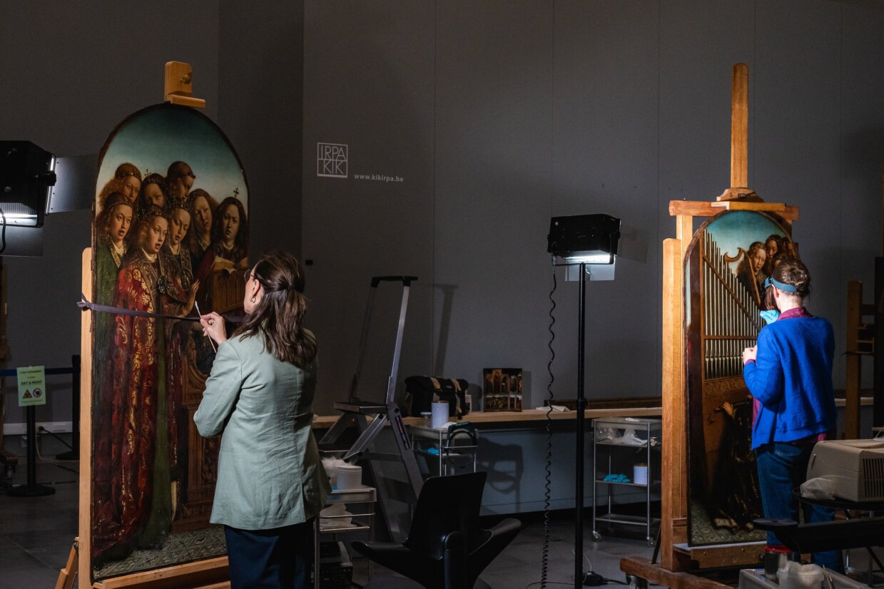 Conservators working behind glass on the Ghent Altarpiece panels during phase-three restoration at MSK Gent.