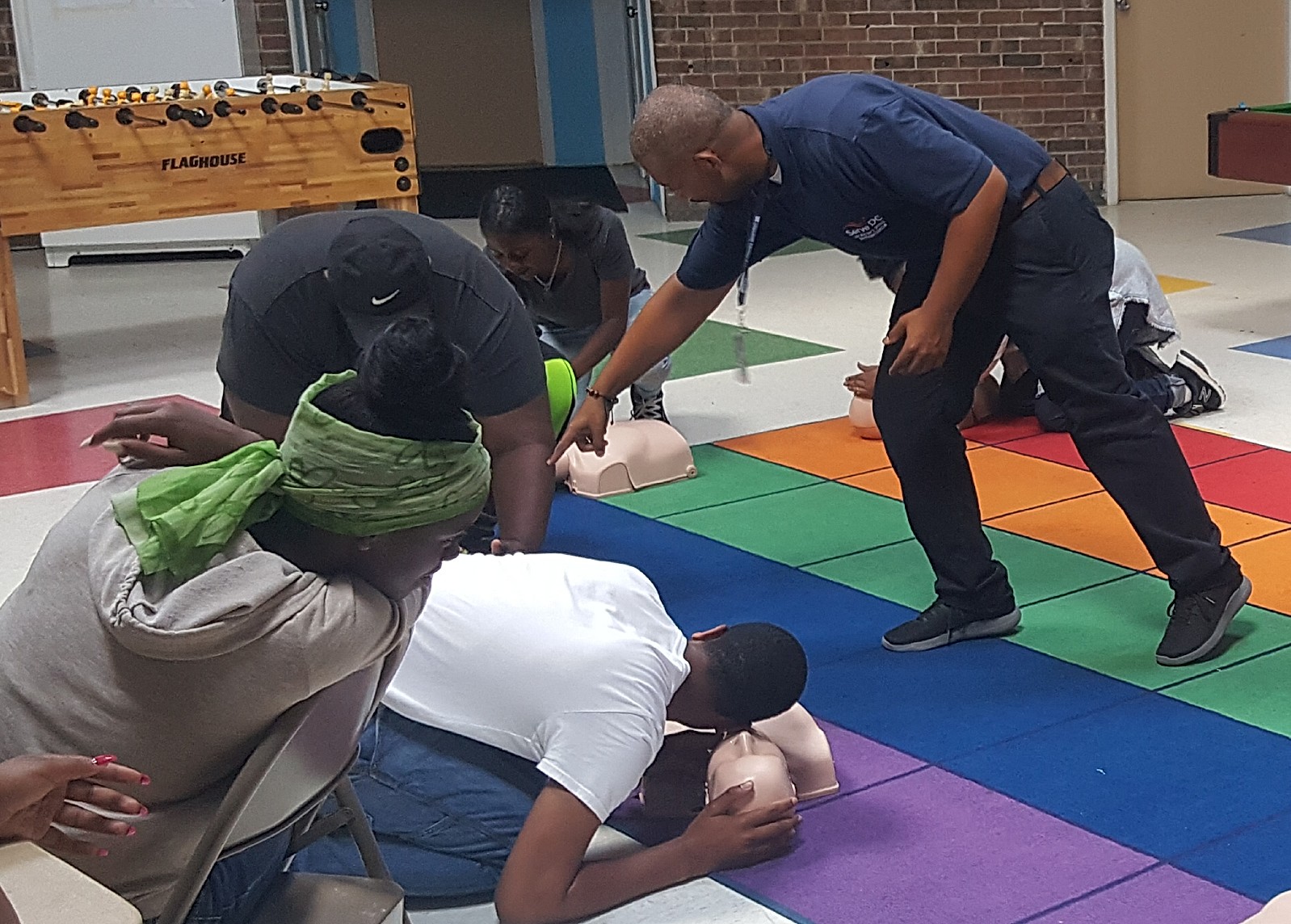 People practicing CPR and AED response on a manikin during a first-aid training session.