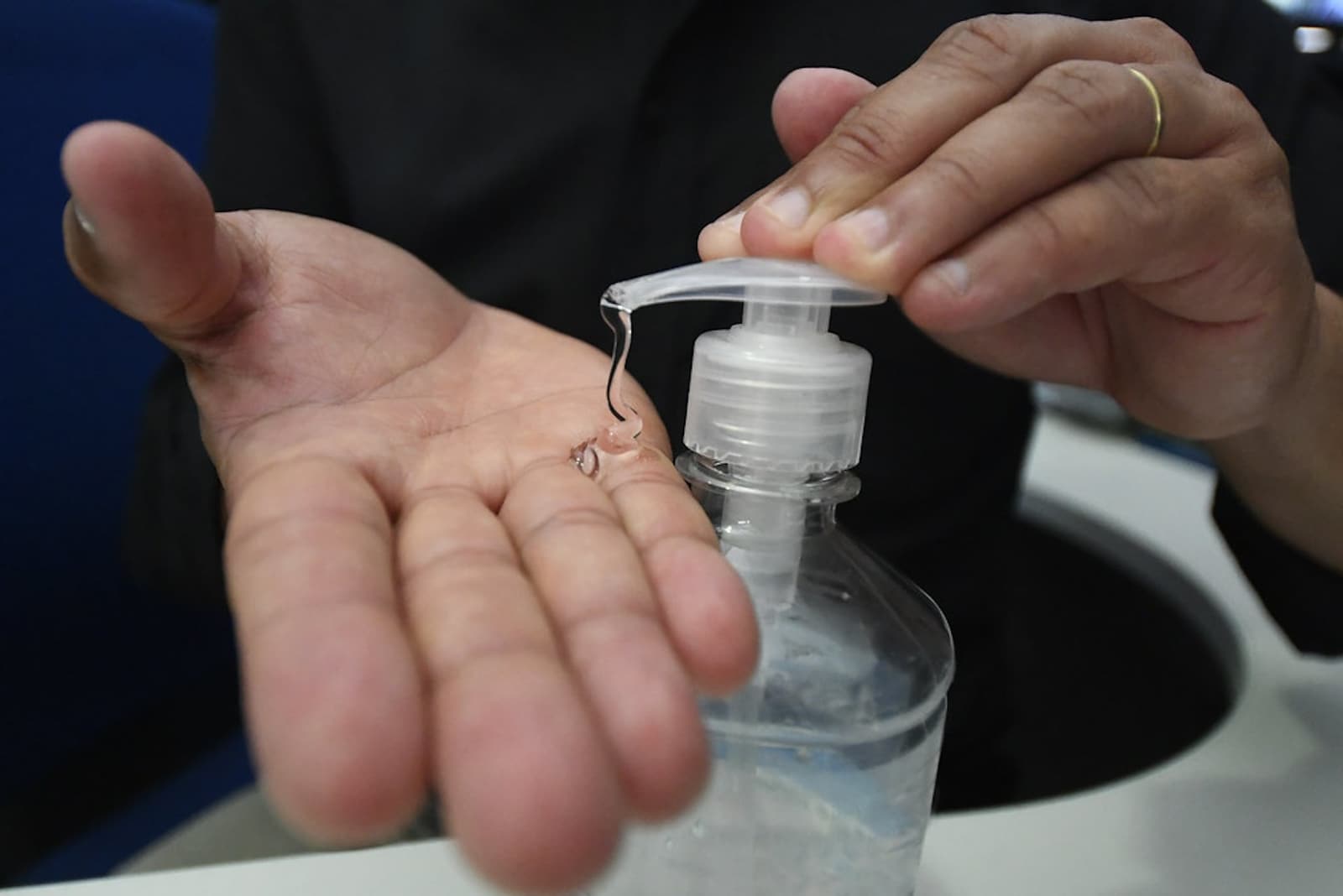 Close-up photograph of alcohol-based hand rub being dispensed into a clinician's palm.