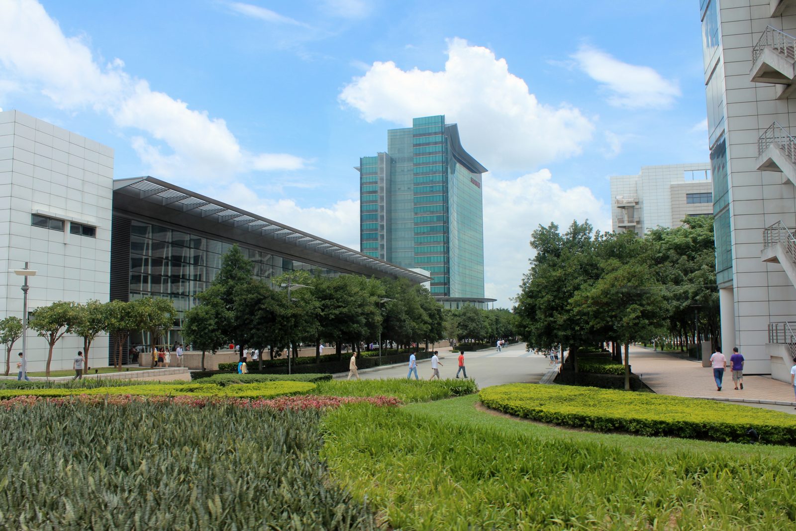 A real photograph of Huawei's Bantian headquarters campus in Shenzhen, with office buildings, trees, and an open central walkway under daylight.