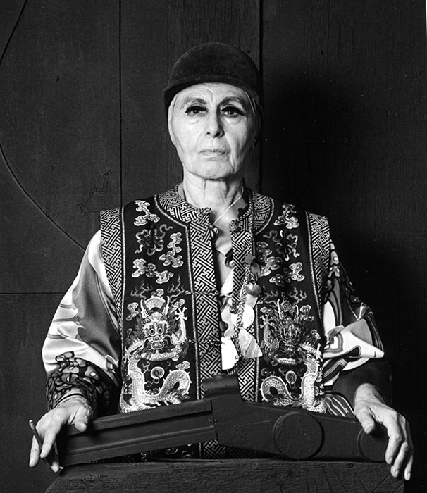 Louise Nevelson, photographed in 1976, faces the camera in dark clothing with dramatic eyelashes and jewelry.