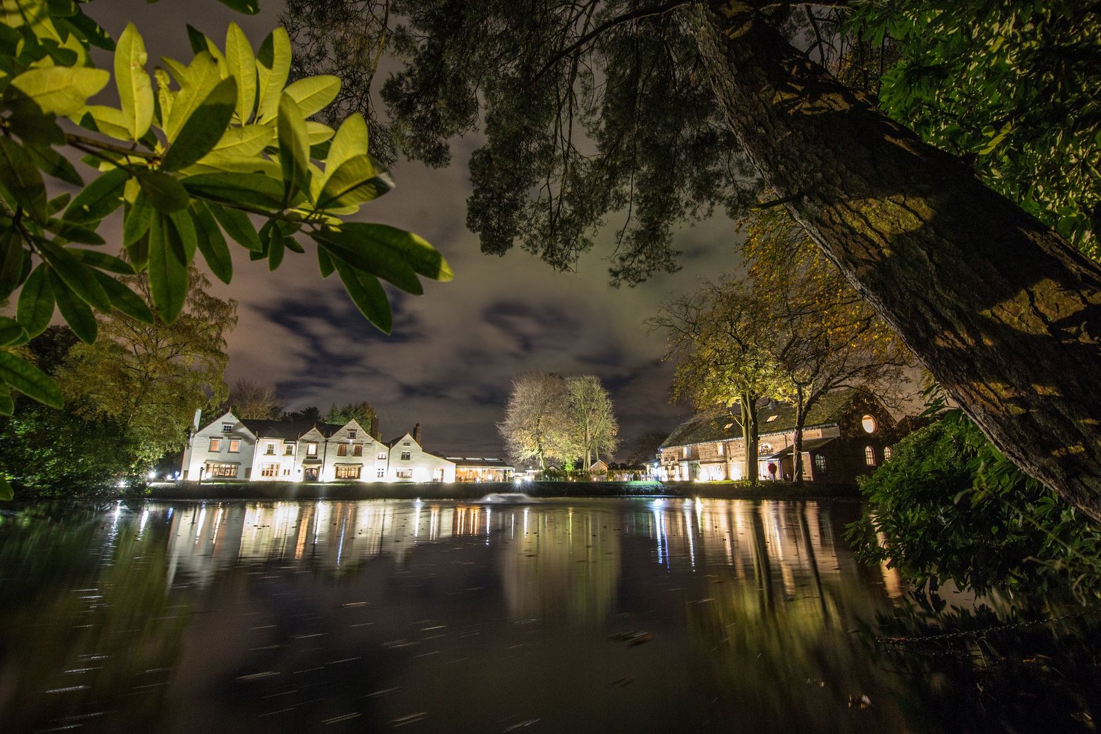 Moor Hall Restaurant with Rooms lit across its lake at night in Aughton, Lancashire.