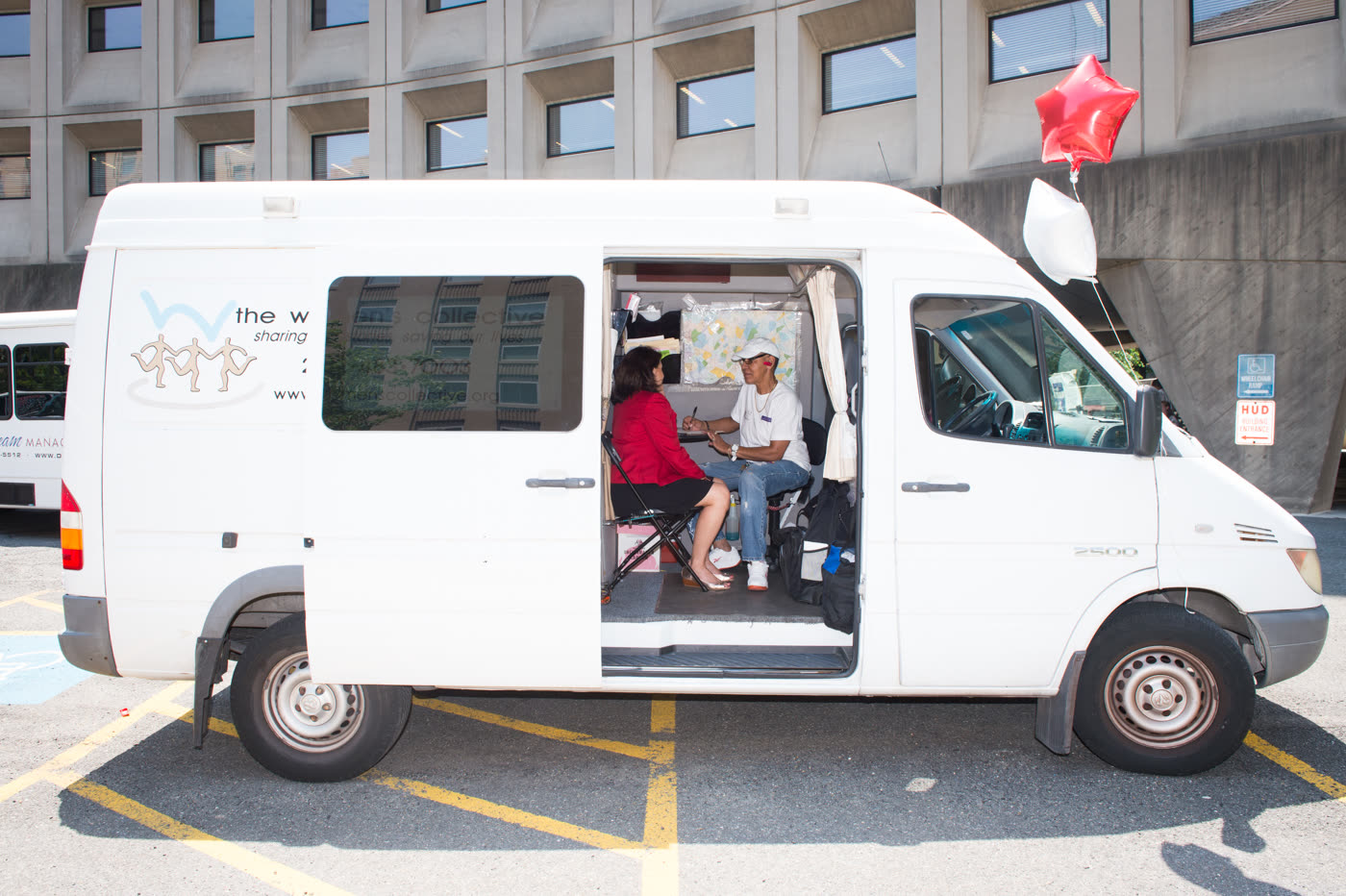 A man and a woman stand behind a table at a National HIV Testing Day outreach event, holding signs and educational materials.