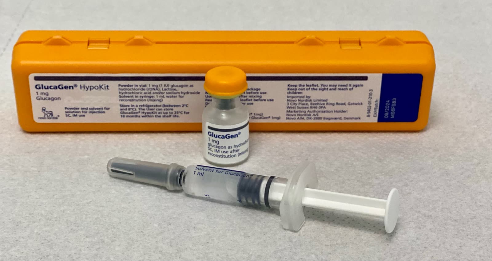 A documentary photograph of a GlucaGen HypoKit case, vial, and syringe laid out on a tabletop.