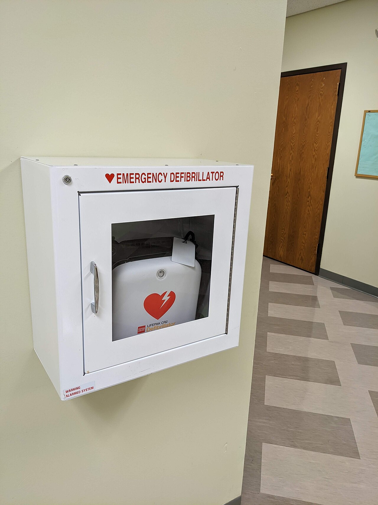 A wall-mounted automated external defibrillator cabinet photographed in a public indoor setting.
