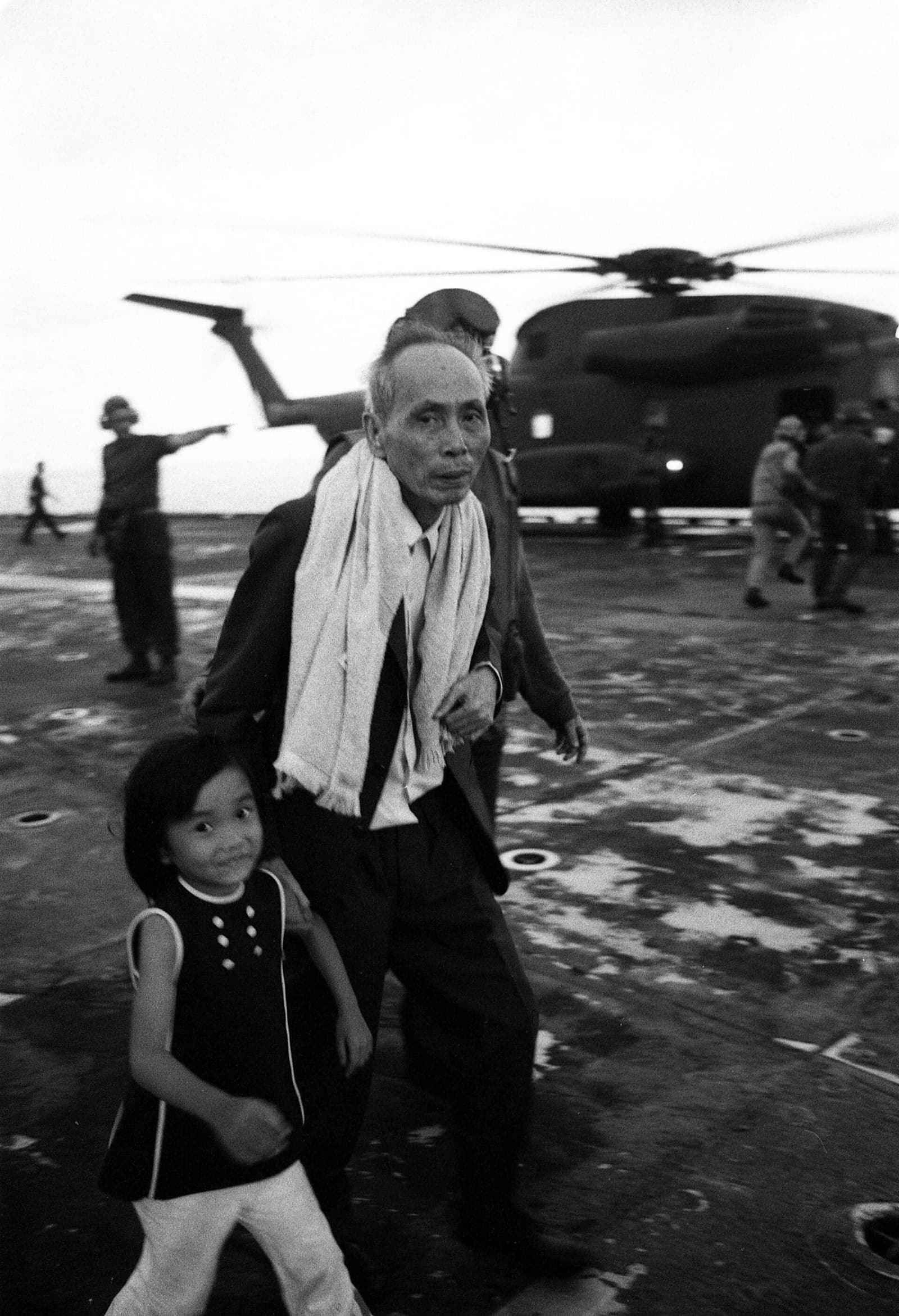 South Vietnamese evacuees walk across the flight deck of the USS Hancock after helicopter evacuation from Saigon on 29 April 1975.