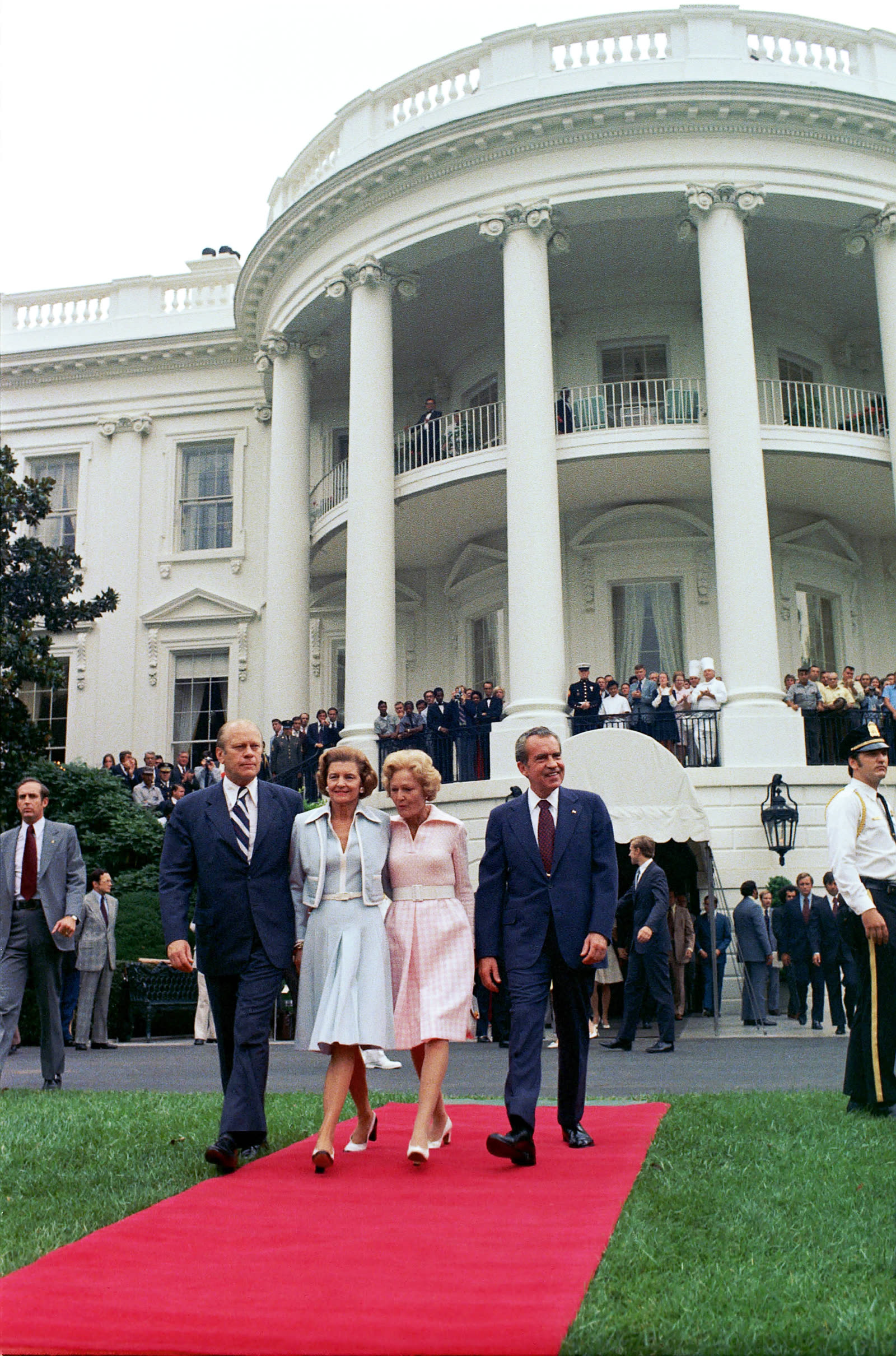 Archival color photograph of Richard and Pat Nixon walking with Gerald and Betty Ford across the South Lawn toward the presidential helicopter on August 9, 1974.