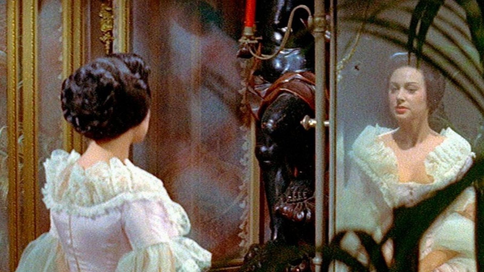 Martine Carol as Lola Montès appears in white costume before a mirror in a color still from Max Ophuls's 1955 film.