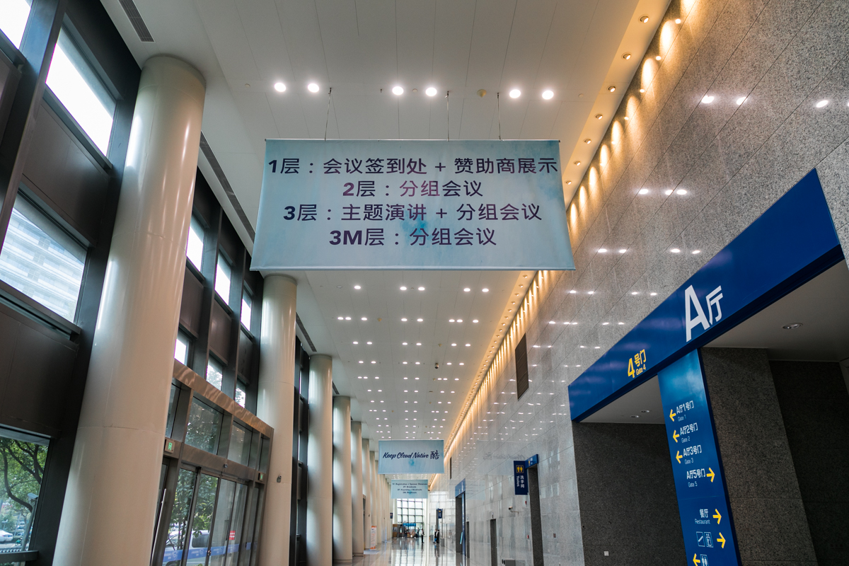 Conference hall interior at KubeCon + CloudNativeCon China, with floor-direction signage in Chinese and event branding visible in the venue space.