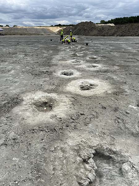 Photograph of a line of dinosaur footprints leading across the excavated quarry floor at Dewars Farm in Oxfordshire.