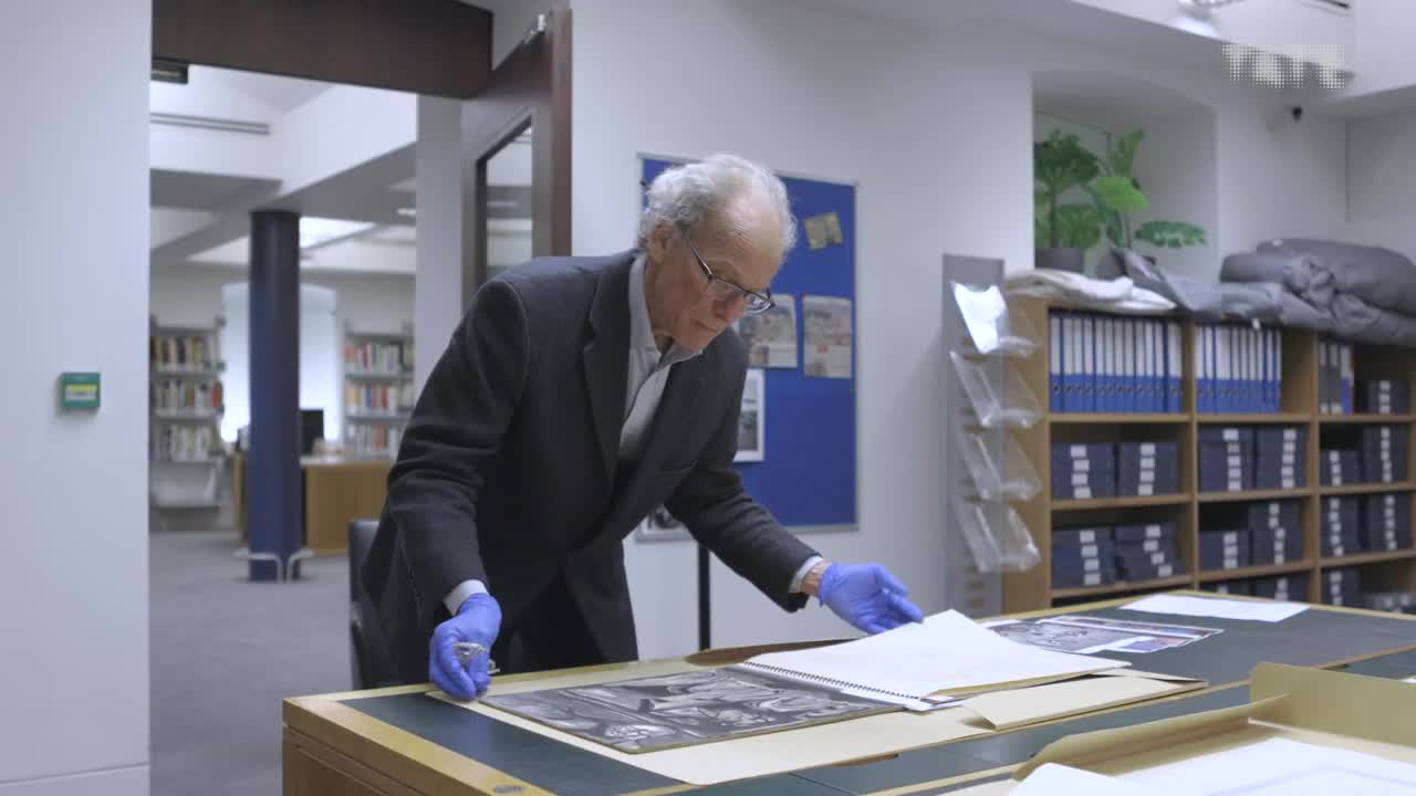 David Aukin leans over an open Jankel Adler sketchbook in Tate's archive reading room.