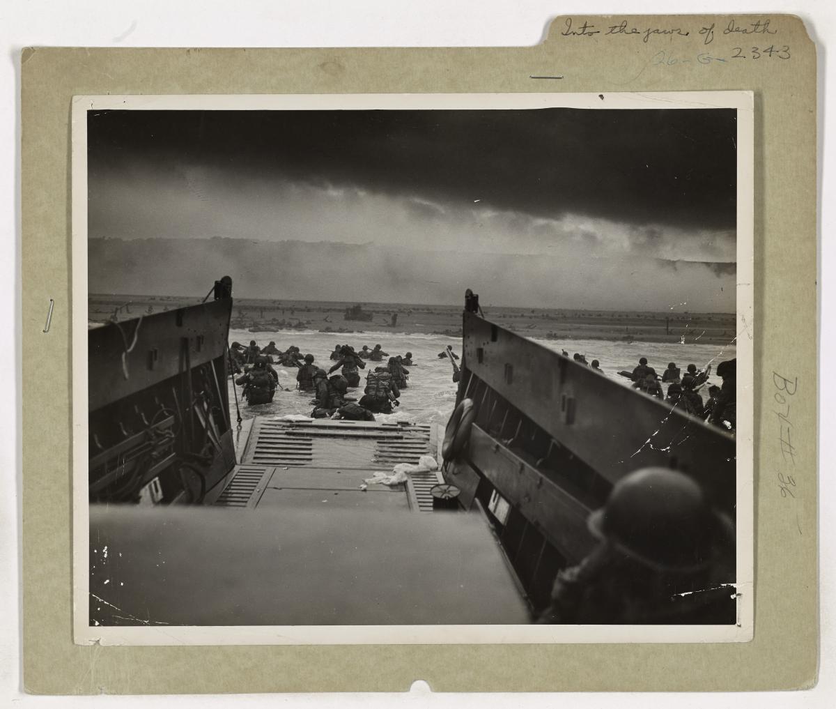 American soldiers of Company E, 16th Infantry, 1st Infantry Division wade through surf toward Omaha Beach on D-Day under enemy fire.