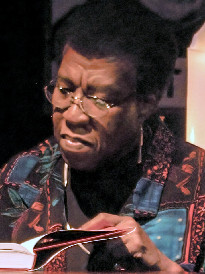 Octavia Butler seated at a book signing table, photographed after speaking with an audience.