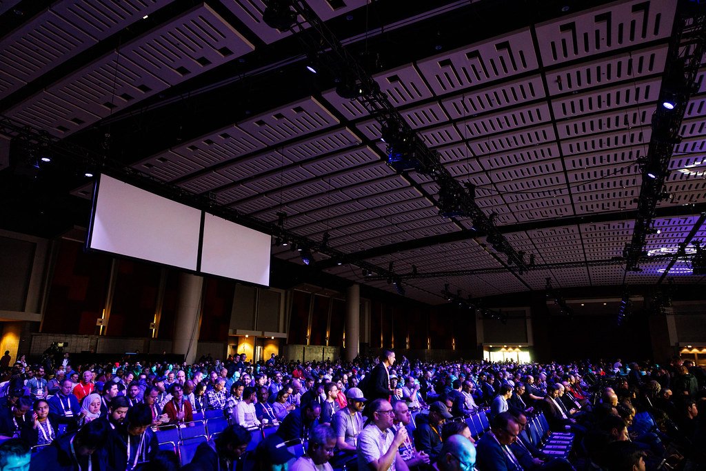 KubeCon and CloudNativeCon North America 2023 的昏暗主题演讲厅里，大批观众面向舞台就座。