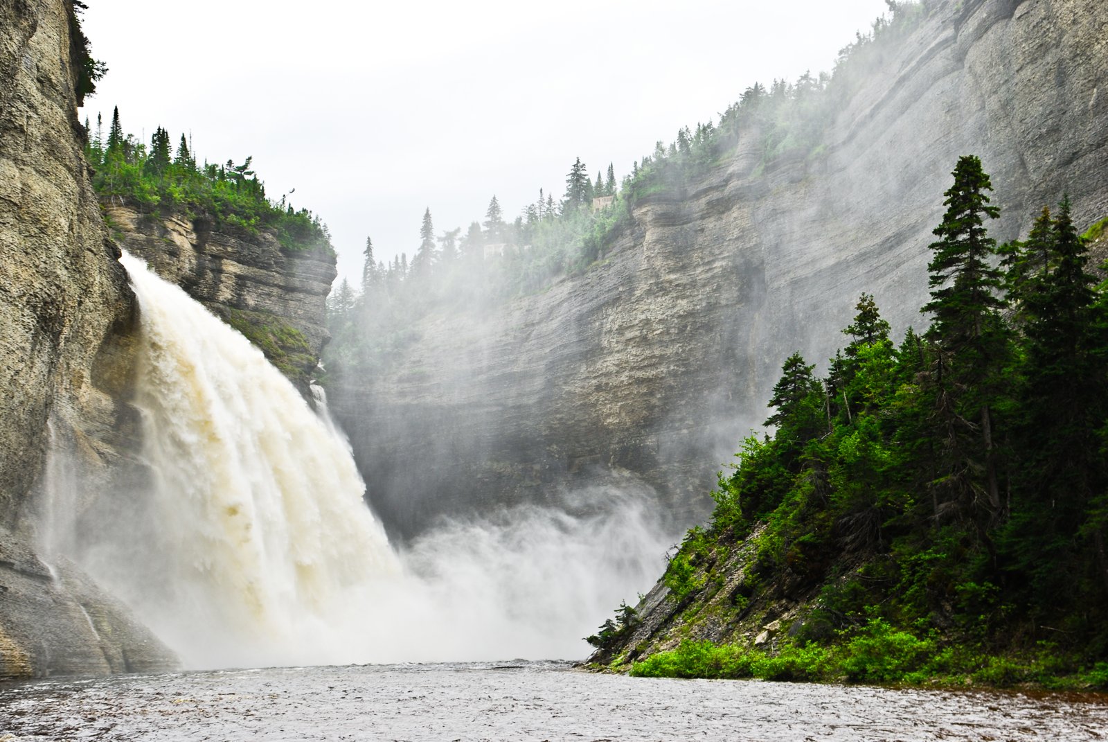 A daylight photograph of Vauréal Falls on Anticosti Island cutting through layered rock exposures.