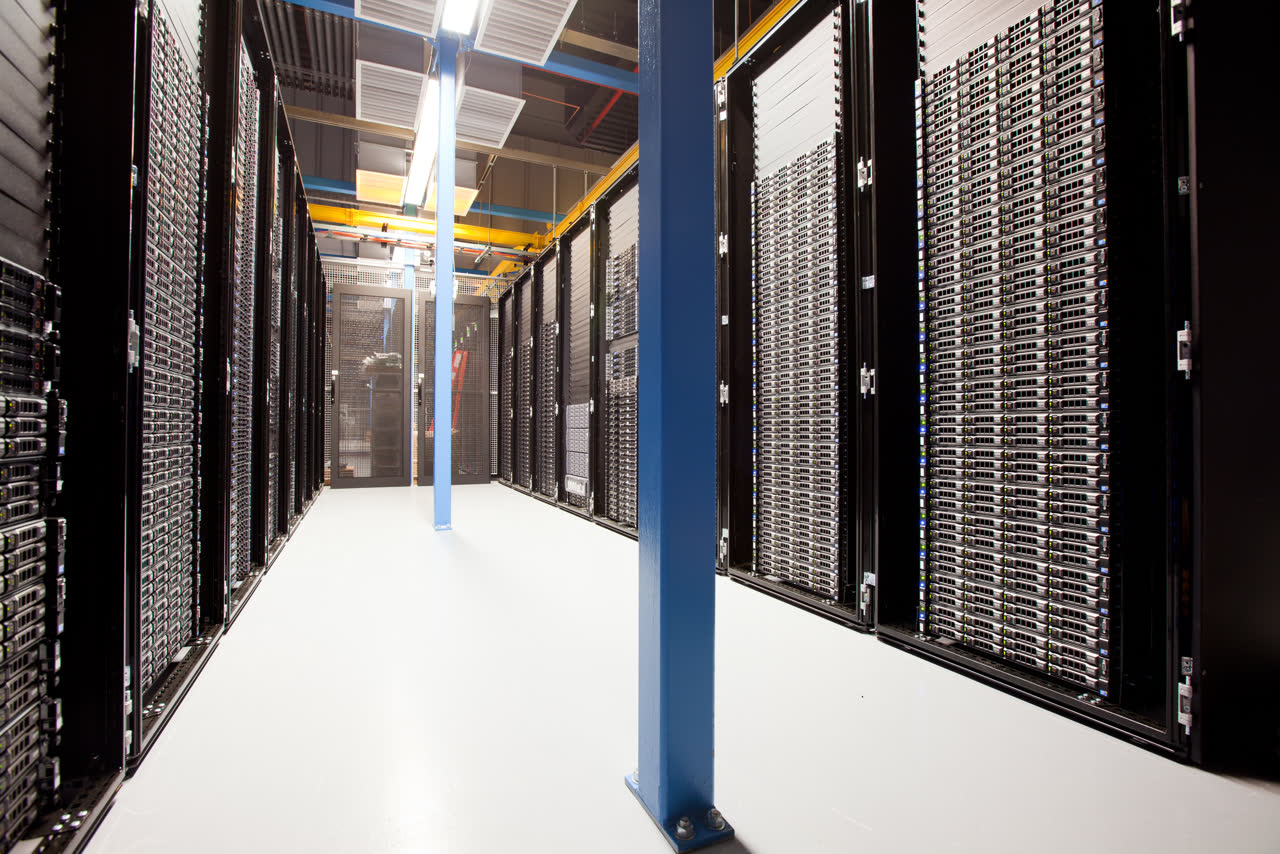 Photograph of rows of black server racks in a bright data-center corridor.