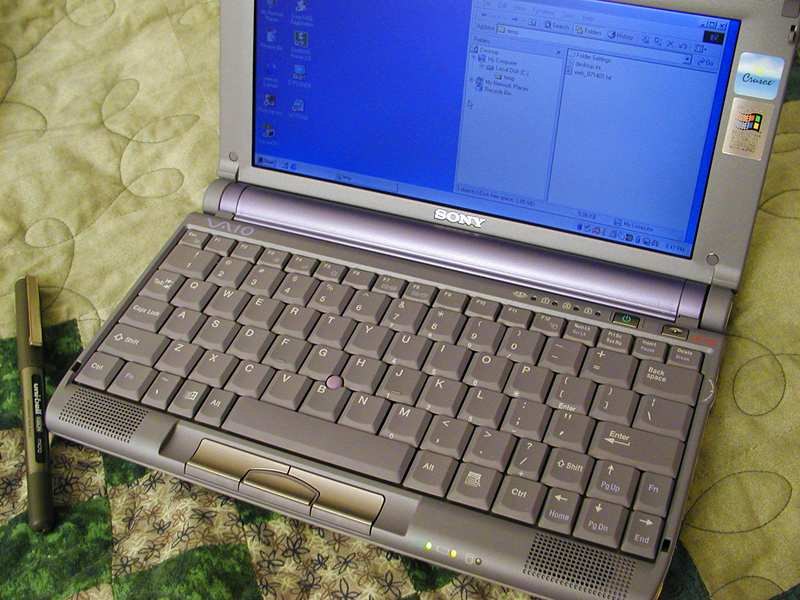 A real photograph of an open laptop on a bed with a pen beside it, used to anchor the article in hands-on browser and web-app work.