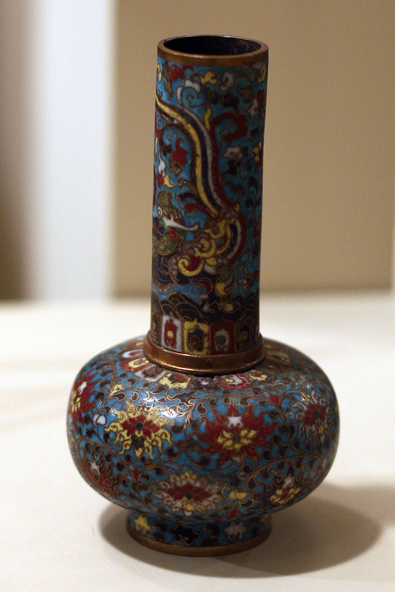 A real museum photograph of an early sixteenth-century Chinese cloisonne enamel vase with dense blue, red, green, and yellow ornament on a copper-alloy body.