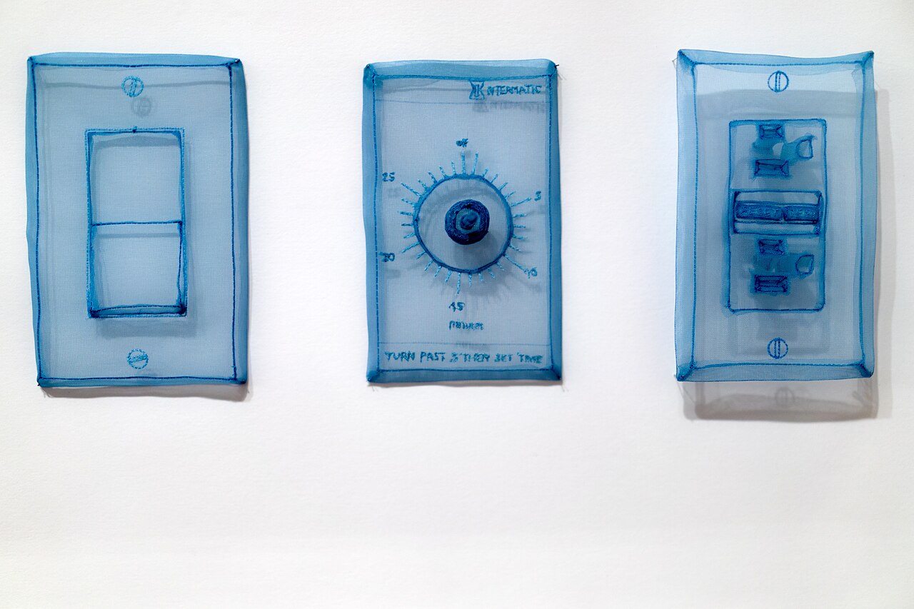 Blue translucent fabric recreations of a light switch, dial, and electrical outlet by Do Ho Suh.