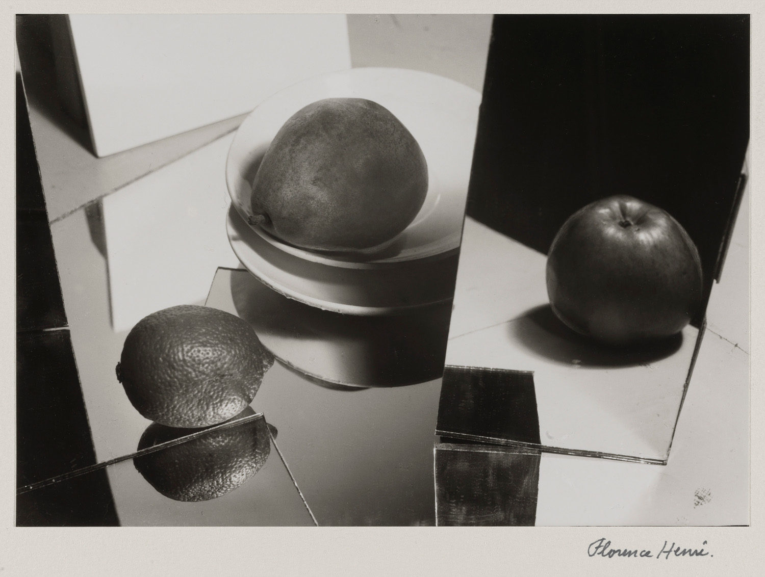 Florence Henri's 1929 black-and-white photograph Fruit, showing citrus fruit, a white plate, mirrors, and sharp geometric shadows.