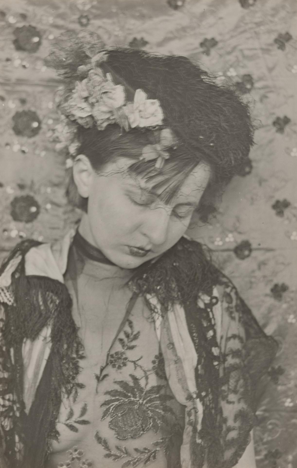 Gertrud Arndt's 1930 Mask self-portrait no. 11, a black-and-white photograph of the artist in veil, flowers, and patterned textiles before a decorated backdrop.