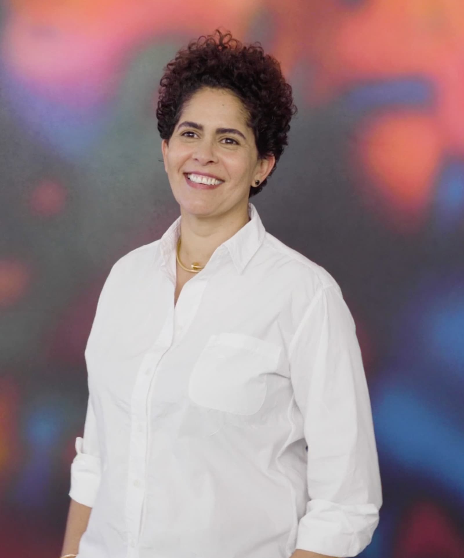 Julie Mehretu 站在工作室里，身旁是一幅大型抽象画。