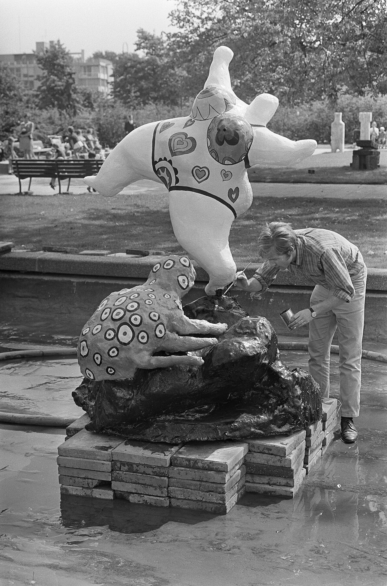一张 1967 年黑白档案照片中，尼基·德·圣法勒站在市立博物馆花园里，身旁是一件大型 Nana 形象。