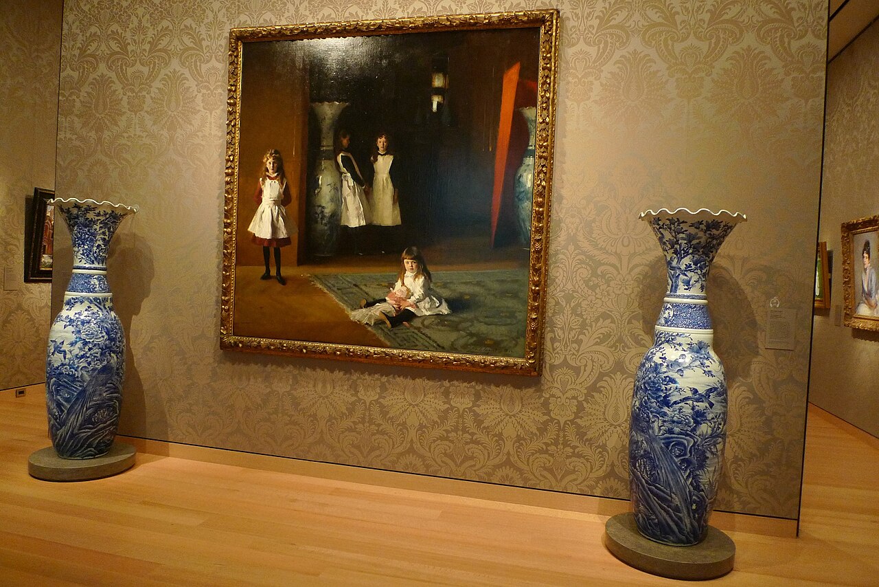 A gallery photograph of John Singer Sargent's The Daughters of Edward Darley Boit hanging between two tall blue-and-white vases in the Museum of Fine Arts, Boston.