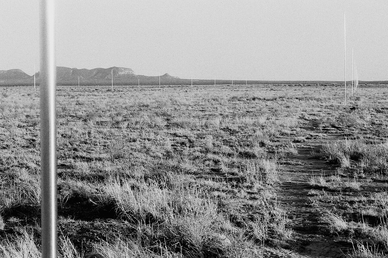 Walter De Maria's The Lightning Field in western New Mexico, with stainless-steel poles standing in a desert grid under a clouded sky.