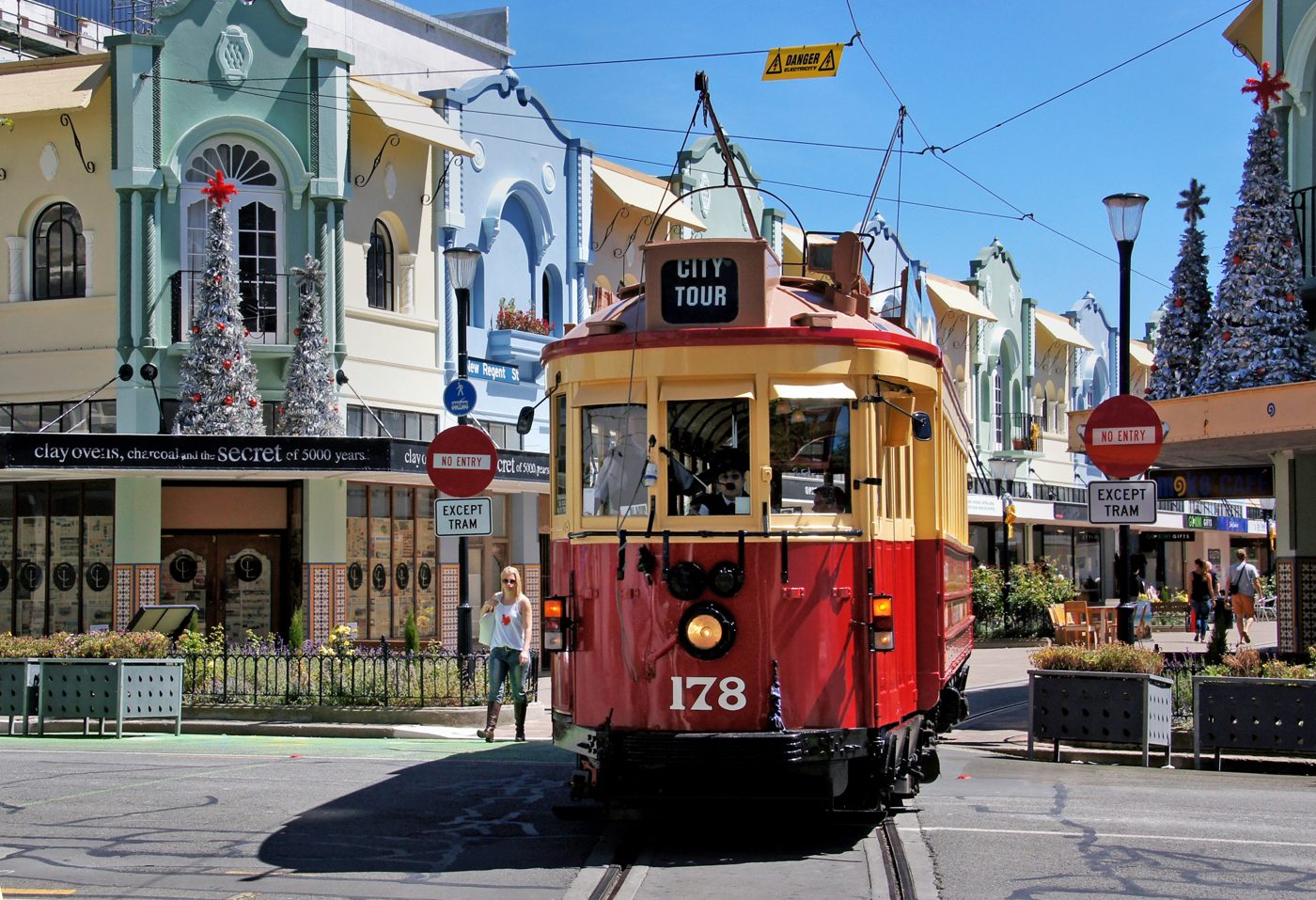 A restored Christchurch heritage tram passing through the pastel facades of New Regent Street.