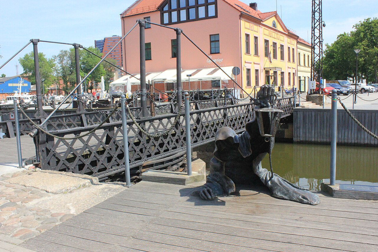 Klaipėda's black iron swing bridge beside the Black Ghost sculpture and castle canal.