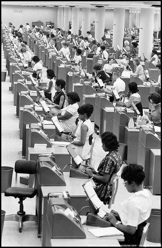 1965 年，马里兰州巴尔的摩一间社会保障办公室内，多排工作人员正在处理记录。
