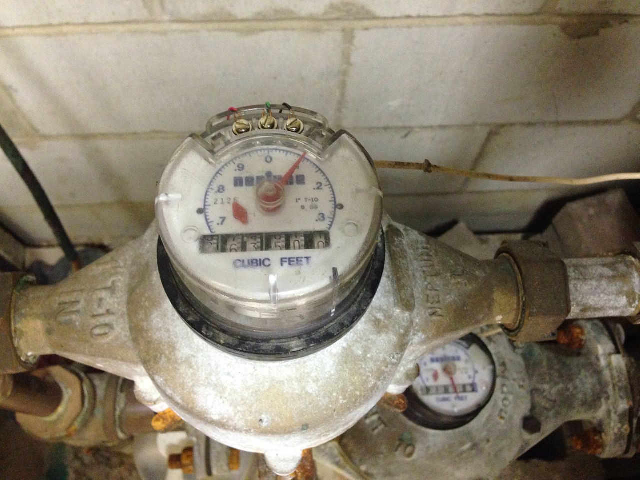 Photograph of two connected water meters with remote-reading wires in a utility space.
