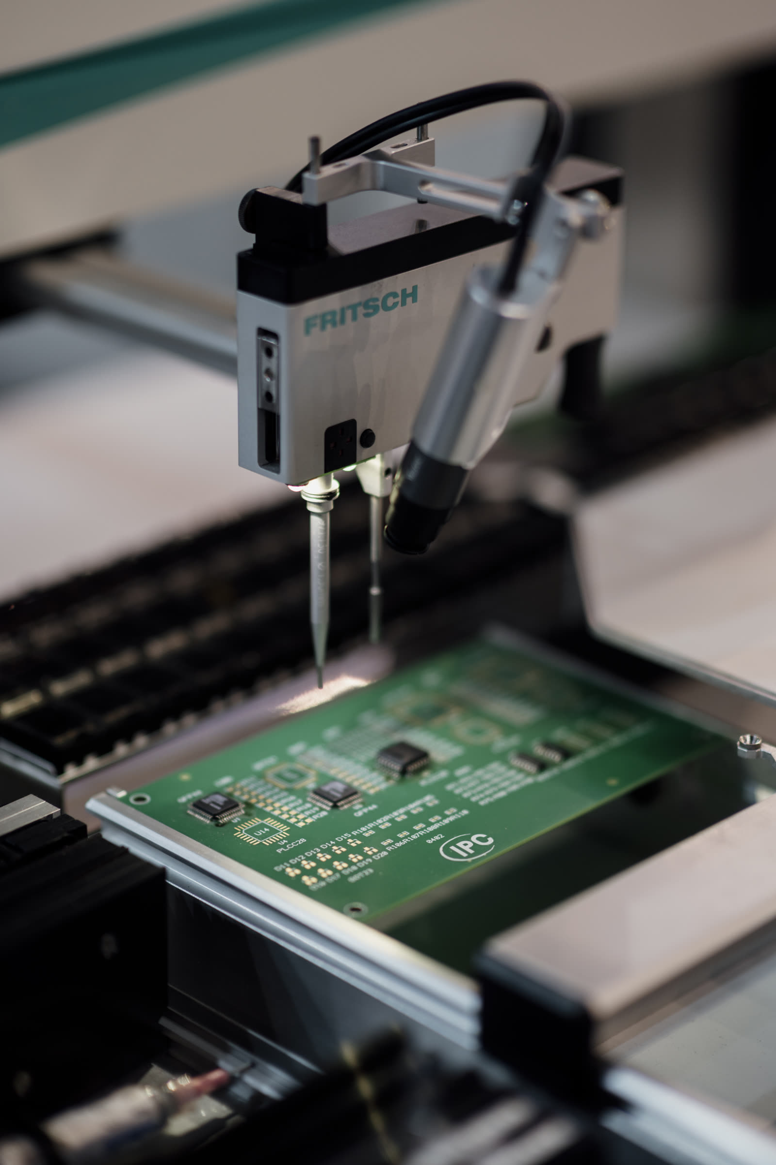 A machine places components onto a circuit board during electronics manufacturing.