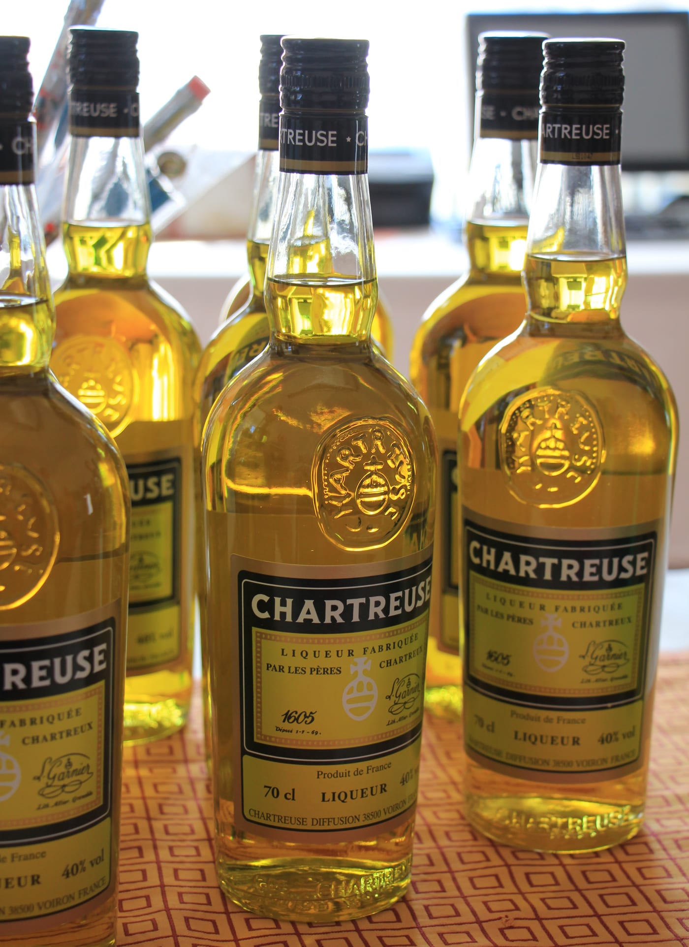 一瓶黄色 Chartreuse 竖立在玻璃柜中，标签和金色利口酒清晰可见。