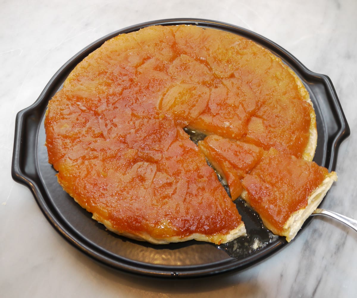 一只焦糖化的 Tarte Tatin 放在白色盘中，完成翻面上桌后由上方拍摄。