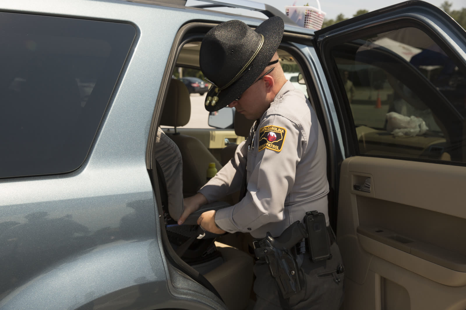 A North Carolina State Highway Patrol trooper tightens straps on a child safety seat during a car-seat inspection event at Camp Lejeune.
