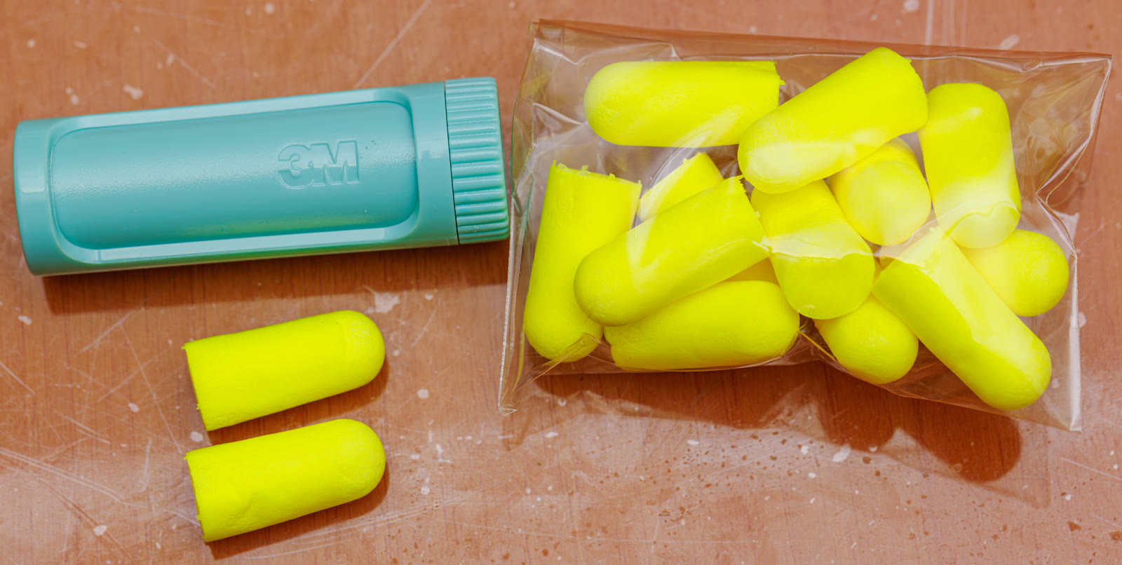 Photograph of yellow foam earplugs arranged on a white surface.