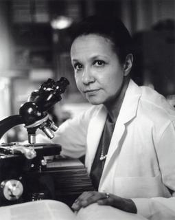 Black-and-white archival photograph of Jane C. Wright in a lab coat beside a microscope.