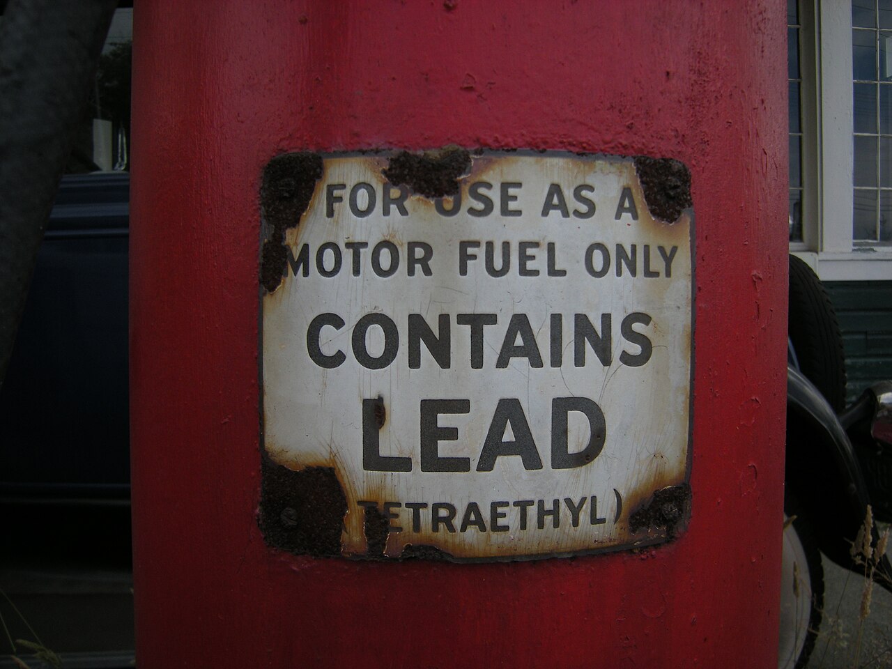 Close-up photograph of a lead warning label on an old gasoline pump.