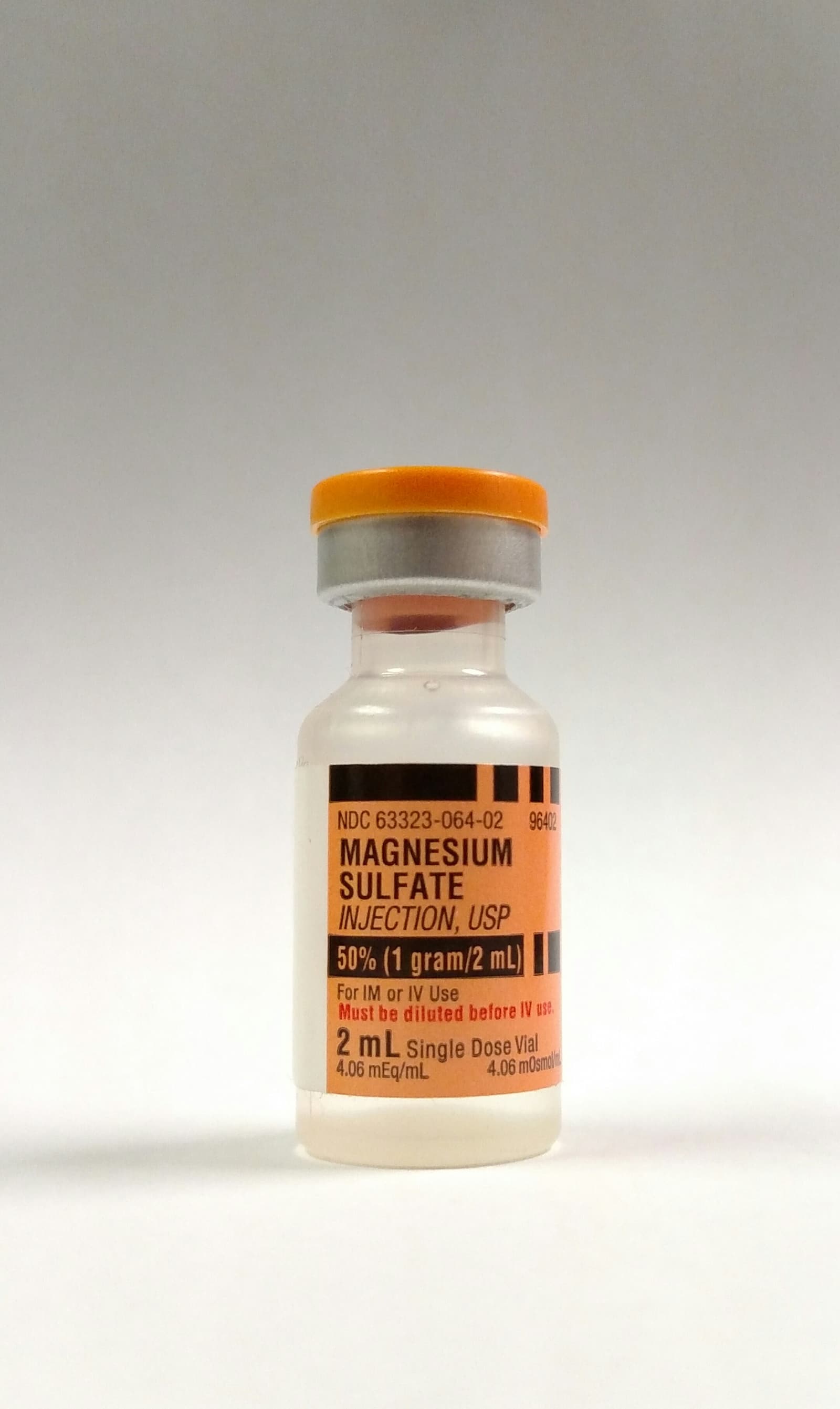 Photograph of an intravenous magnesium sulfate vial held in a clinical hand.