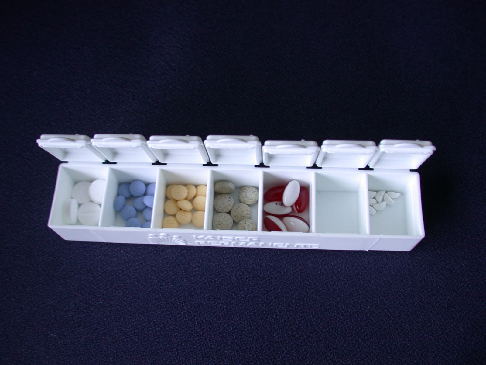 An open plastic pill organizer filled with assorted medicines.