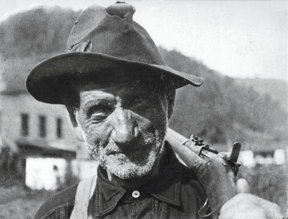 Black-and-white archival photograph of a coal miner from the Blair Mountain period holding a rifle over his shoulder.