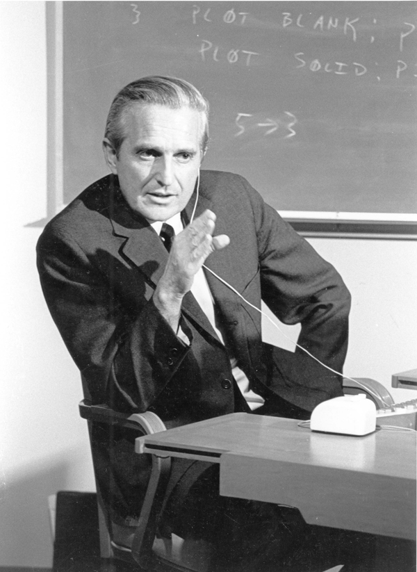 1968 年 Douglas Engelbart 坐在控制台前为“所有演示之母”排练的黑白档案照片。