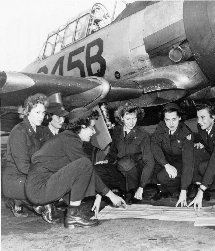 Black-and-white 1943 photograph of Women Airforce Service Pilot trainees at Avenger Field studying a flight plan beside a T-6 Texan aircraft.