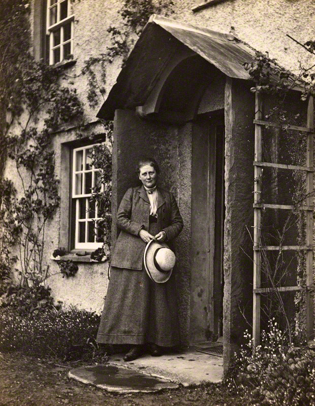 Archival portrait photograph of Beatrix Potter standing in a doorway at Hill Top in May 1913.