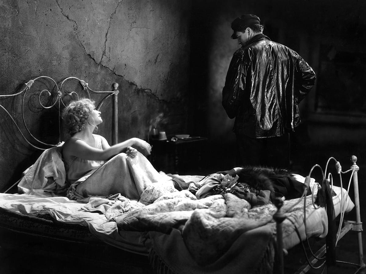 A 1928 Paramount publicity photograph from The Docks of New York showing Betty Compson and George Bancroft seated close together in dark waterfront costume.