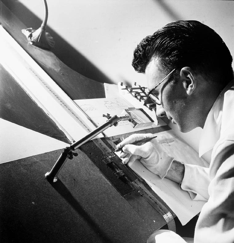 Norman McLaren drawing directly onto a strip of film in a 1944 archival photograph.