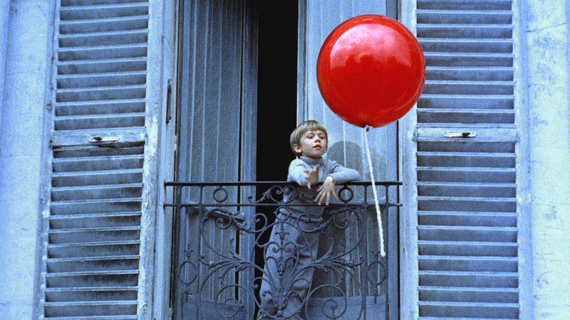 Pascal Lamorisse leans over a Paris apartment balcony beside the glossy red balloon in Albert Lamorisse's 1956 film The Red Balloon.